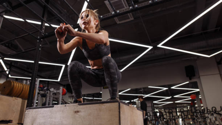 fit young ambitious blond woman doing a box jump exercise.hobby. side view full length photo. people concept